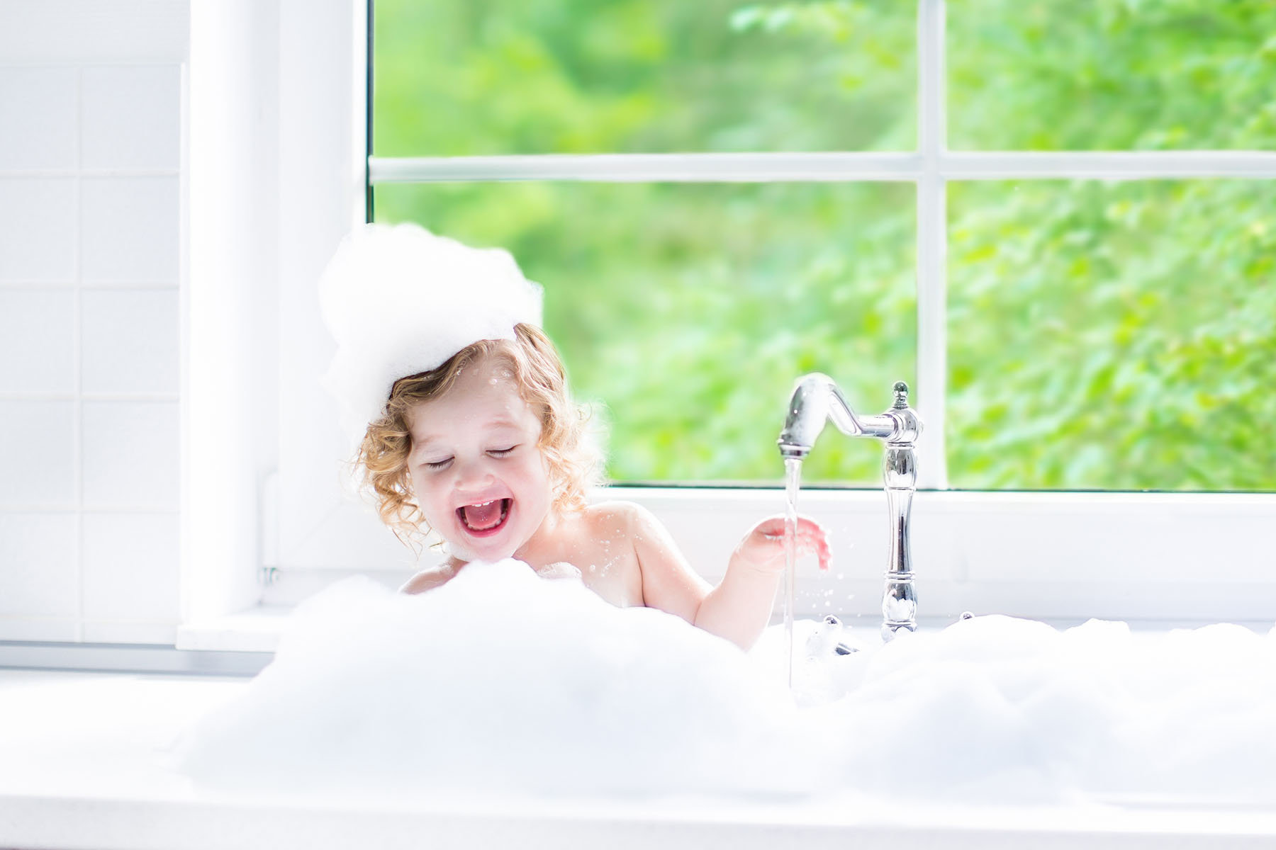child in bubble bath with clean window in the background