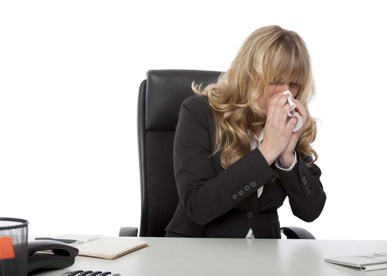 Employee sneezing at desk