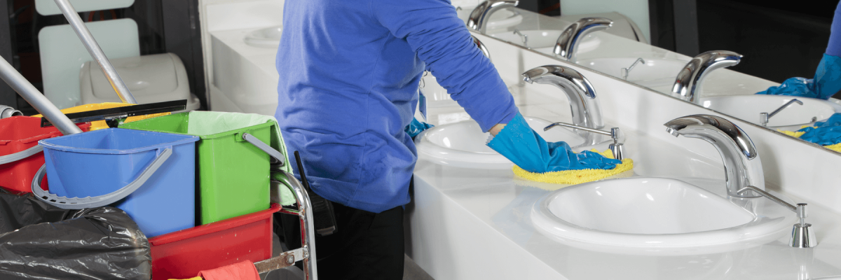 Lady wearing gloves wiping counter in business restroom 