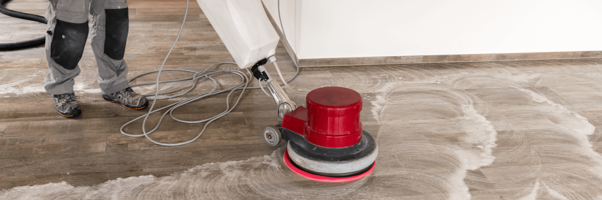 Cleaner using a red rotary floor scrubber on hard surface floor