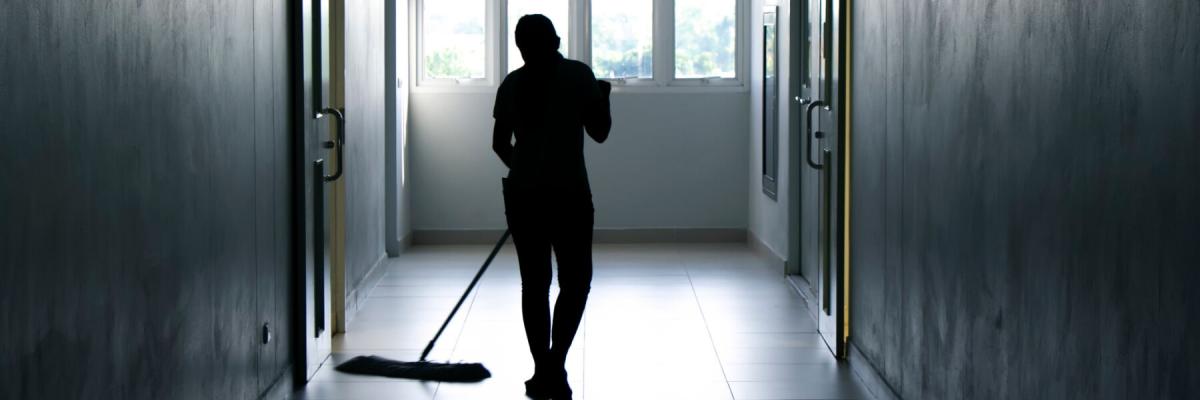 silhouette of janitor mopping a hallway