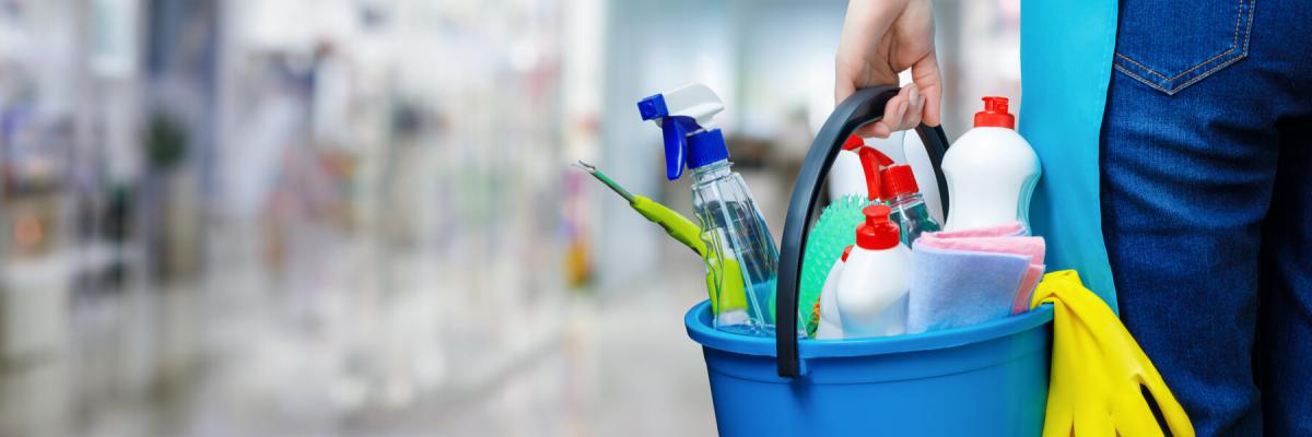 commercial cleaner in building holding bucket of cleaning products